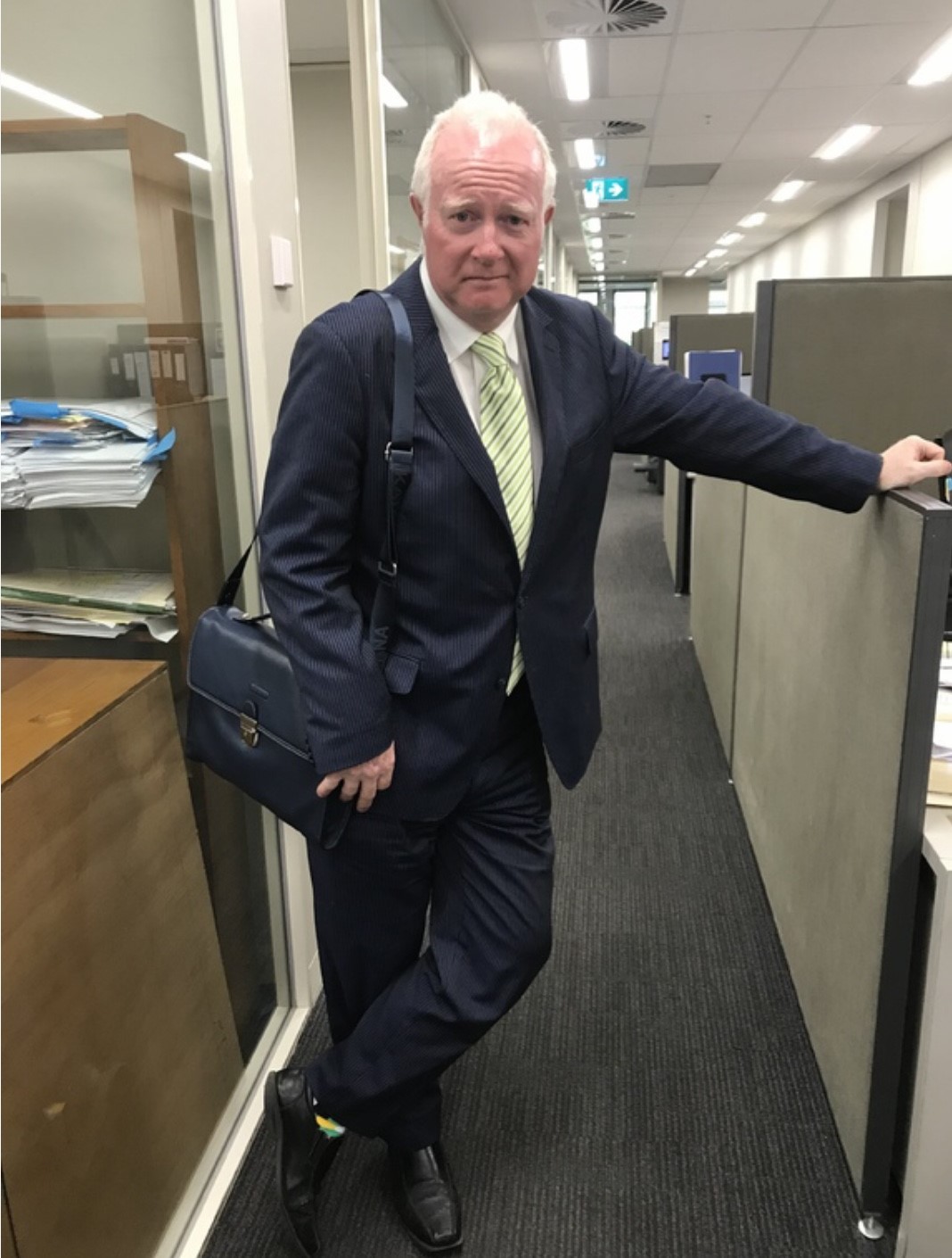 A person in a suit leaning on a wall  Description automatically generated with medium confidence